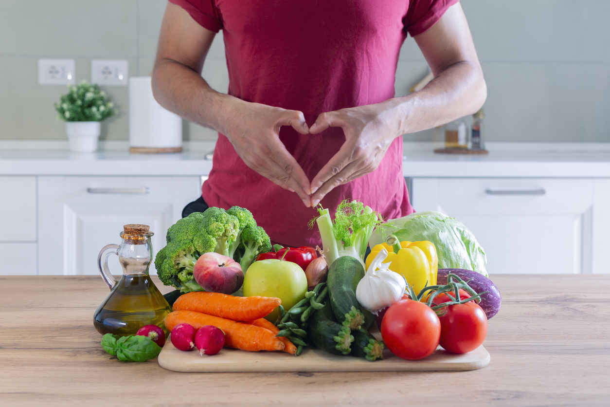 Fresh vegatables on a wooden table with man doing love heart with hands